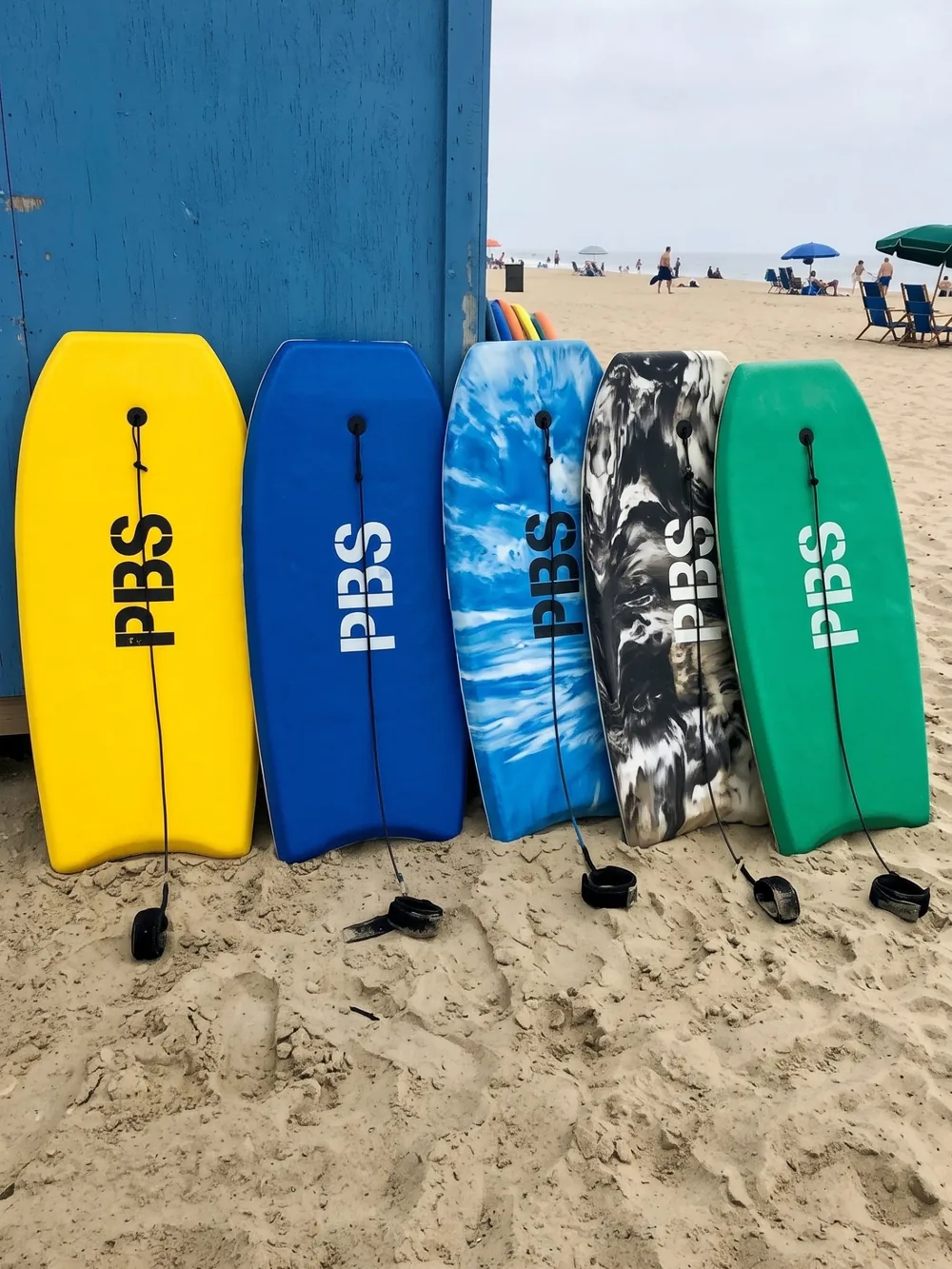 Bunte Boogieboards, die neben einer blauen Strandhütte aufgereiht sind